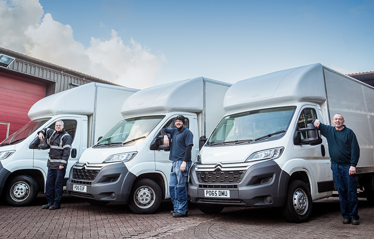 Three technicians waiting by their vans